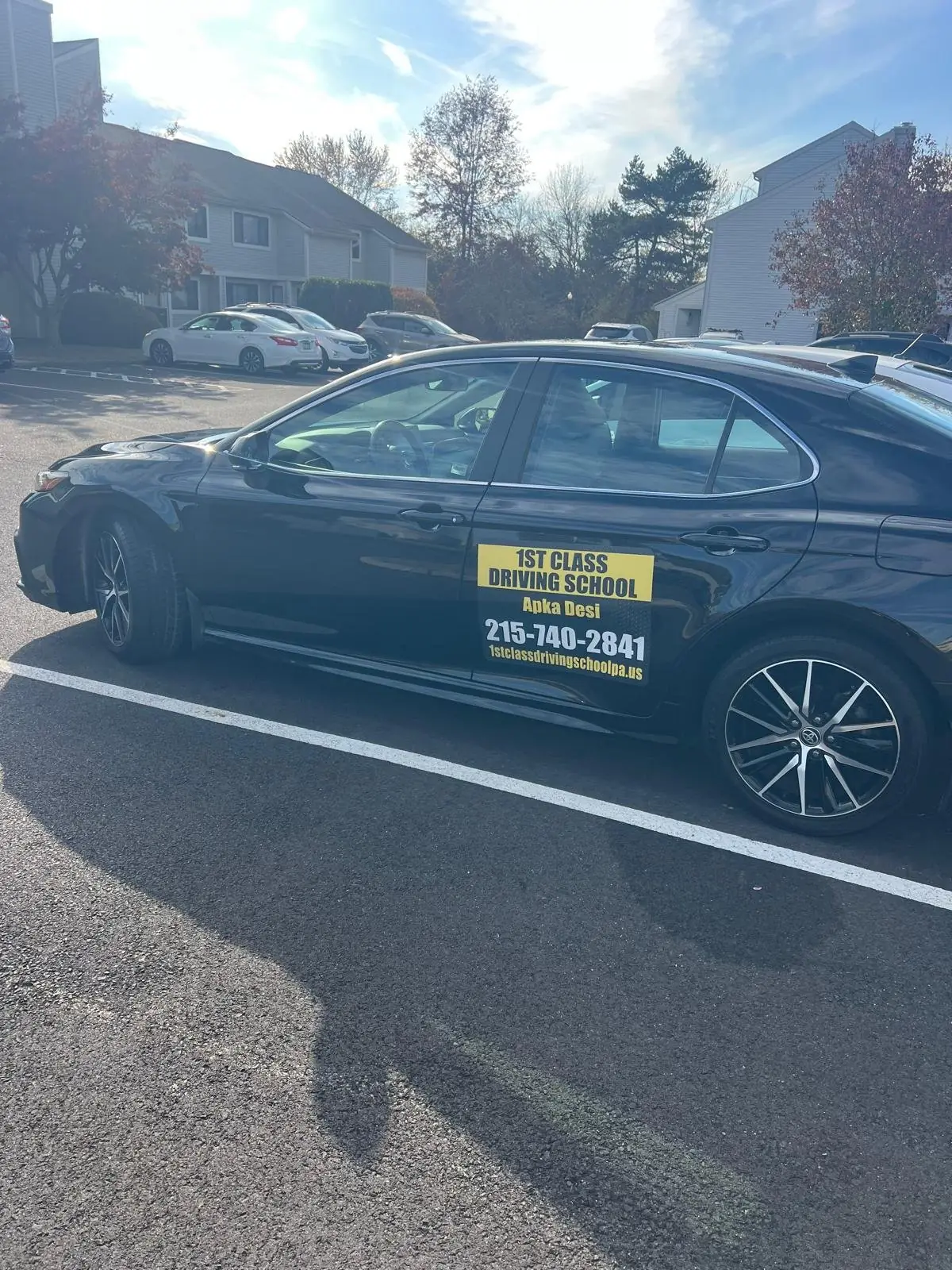 Black training car parked under autumn trees between lessons