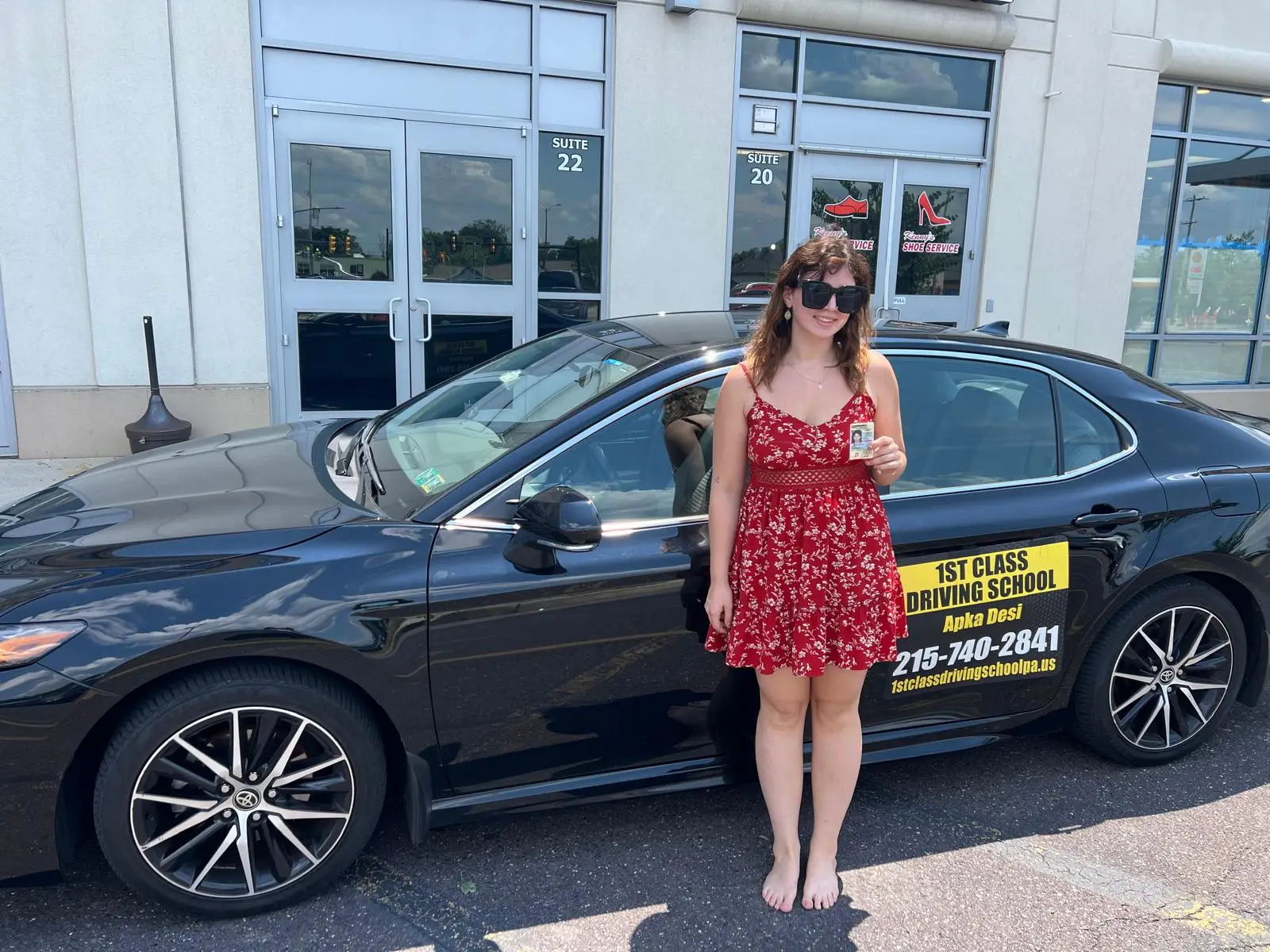 Student standing beside the black training car outside a driver license center