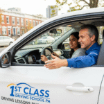 A patient driving instructor from 1st Class Driving School giving a lesson in a car with Philadelphia's City Hall in the background.