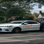 A white student driver training car parked on a residential street in Bristol PA 19007.
