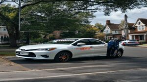 A white student driver training car parked on a residential street in Bristol PA 19007.