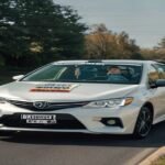 A dual-control training car from a professional driving school in Levittown PA driving on a local road